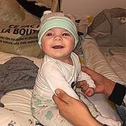 Kayden participe au concours pour gagner de l'argent avec cette photo : baby, child, smiling, hat, pajamas, bed, blanket, pillow, hands, person, indoor, cute, happy, infant, sleepwear, fabric, bedroom, soft, comfort, holding