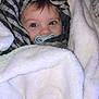 baby, blanket, pacifier, face, headwear, striped_scarf, soft_texture, cozy, wrapped, infant, child, cute, eyes, warm, indoor, comfort, portrait, sleepy, snug, closeup