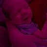arms, baby, blanket, child, close_up, clothing, cuddling, dim_lighting, face, family, head, indoor, infant, mouth, nose, portrait, purple_lighting, seated, sleeping, snuggling