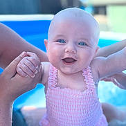 Lottie joined the competition — help win amazing prizes! baby, child, smiling, swimsuit, pink_clothing, hands, pool, water, outdoor, sunlight, happy, face, blue, summer, people, skin, person, infant, excitement, playful