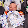 baby, blanket, car_seat, child, comfort, cozy, cute, head_support, indoor, infant, newborn, orange_clothing, peaceful, portrait, resting, safety_belt, sleeping, smile, soft_toy, toddler