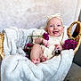 baby, basket, blanket, child, clothing, cozy, cute, flower, happy, headband, indoor, infant, peaceful, plush, portrait, purple_flower, relaxing, sitting, skin, smile