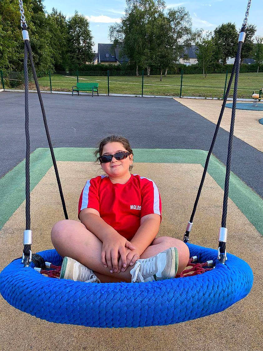 Lia a rejoint le concours — aidez-le/la à gagner de superbes lots ! city, comfort, electric_blue, eyewear, fun, goggles, grass, joy, lap, leg, leisure, outdoor_play_equipment, person, plant, playground, recreation, shade, shorts, sky, sunglasses