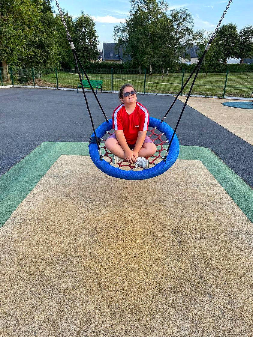 Lia participe au concours pour gagner de l'argent avec cette photo : asphalt, automotive_tire, balance, city, concrete, electric_blue, flooring, grass, hat, leisure, outdoor_play_equipment, person, playground, pole, recreation, road_surface, sky, swing, t_shirt, tire