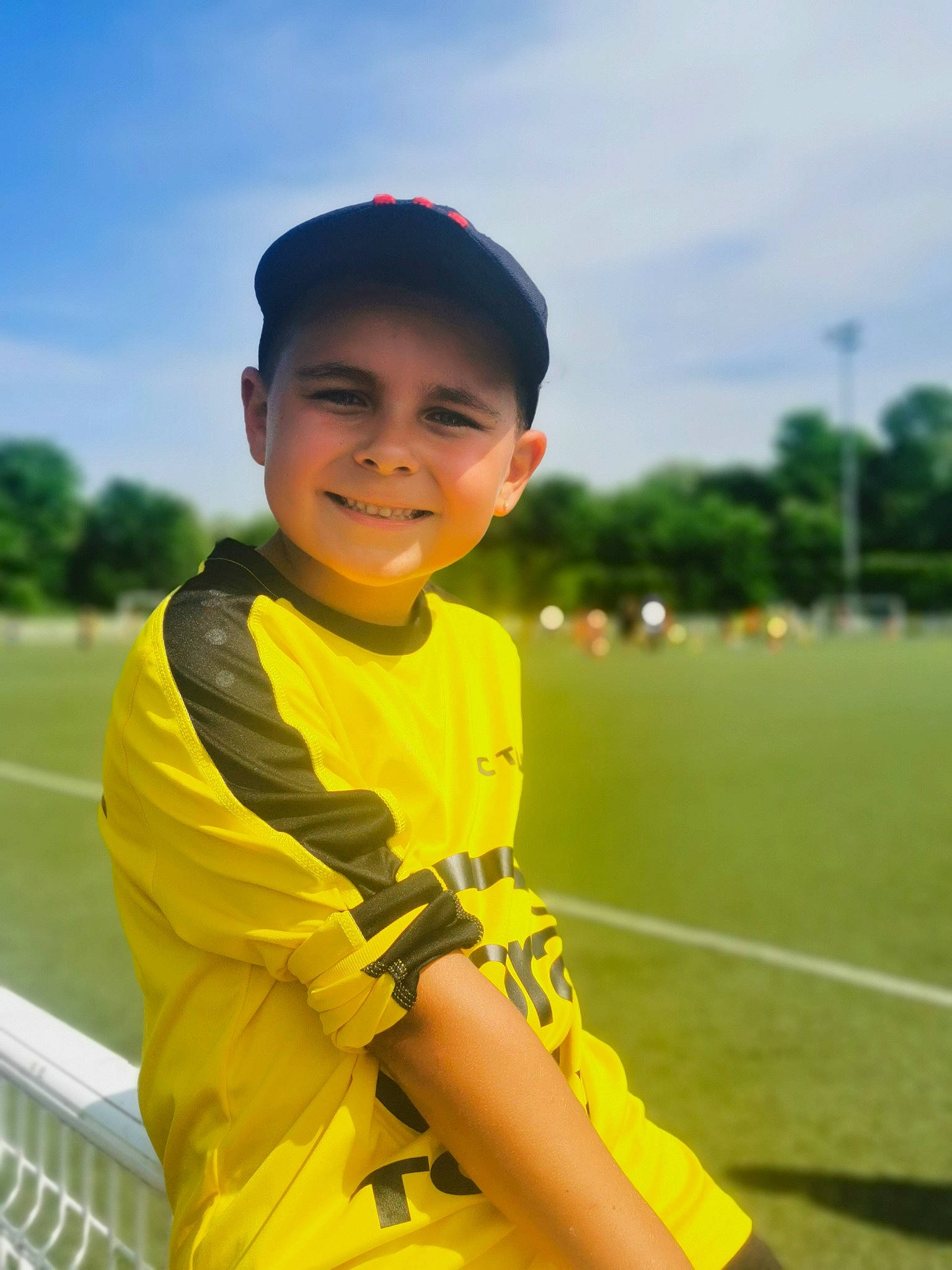 Manöa participe au concours pour gagner de l'argent avec cette photo : baseball_cap, cap, child, electric_blue, fun, grass, grassland, happy, headwear, joy, leisure, people_in_nature, person, recreation, sitting, sky, sleeve, smile, t_shirt, toddler