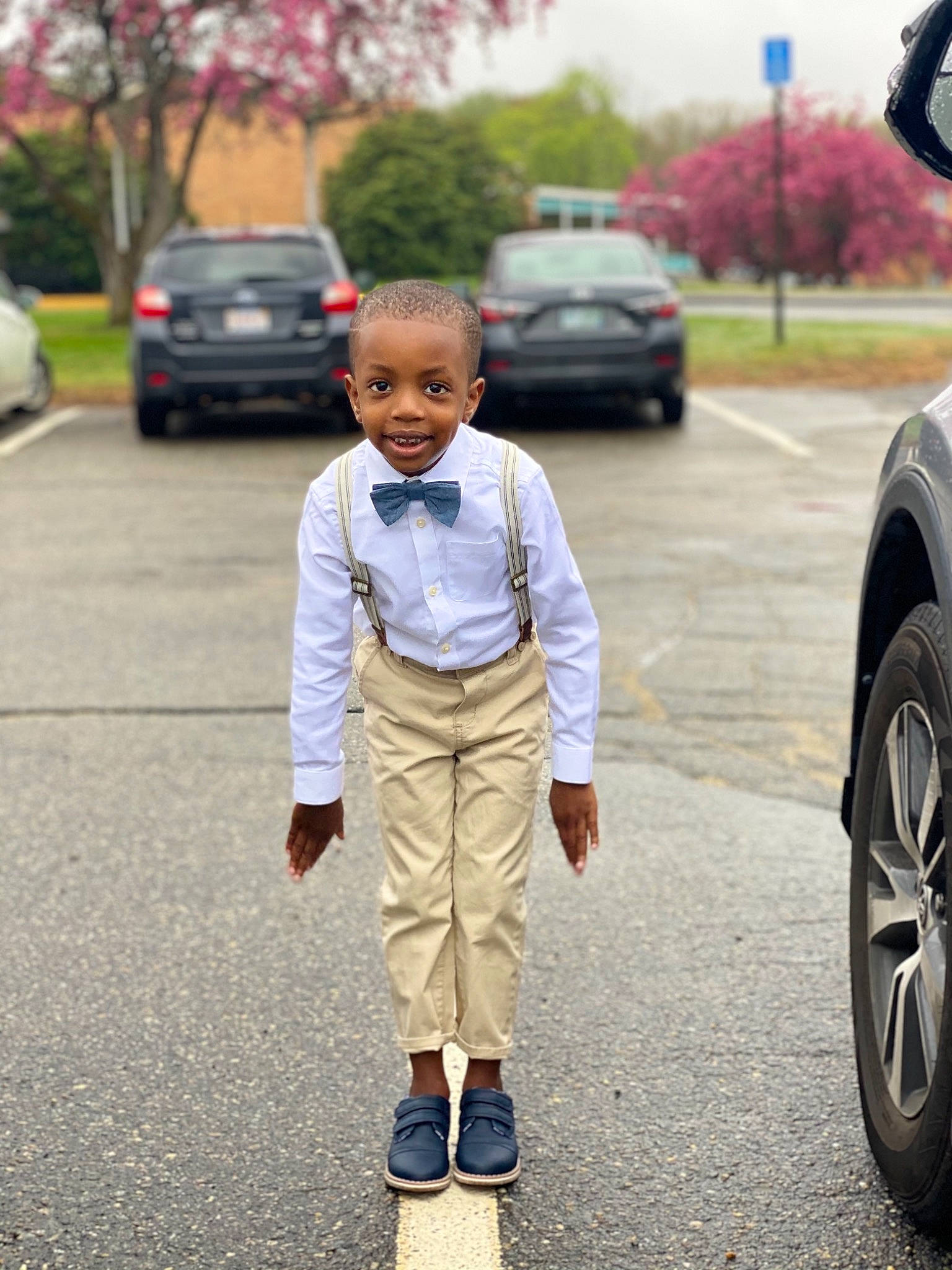 Jabez is registered to the contest to win money with this photo: asphalt, car, child, footwear, formal_wear, gesture, hair, happy, infrastructure, joy, land_vehicle, motor_vehicle, person, road, rolling, shoe, street_fashion, tire, toddler, tree