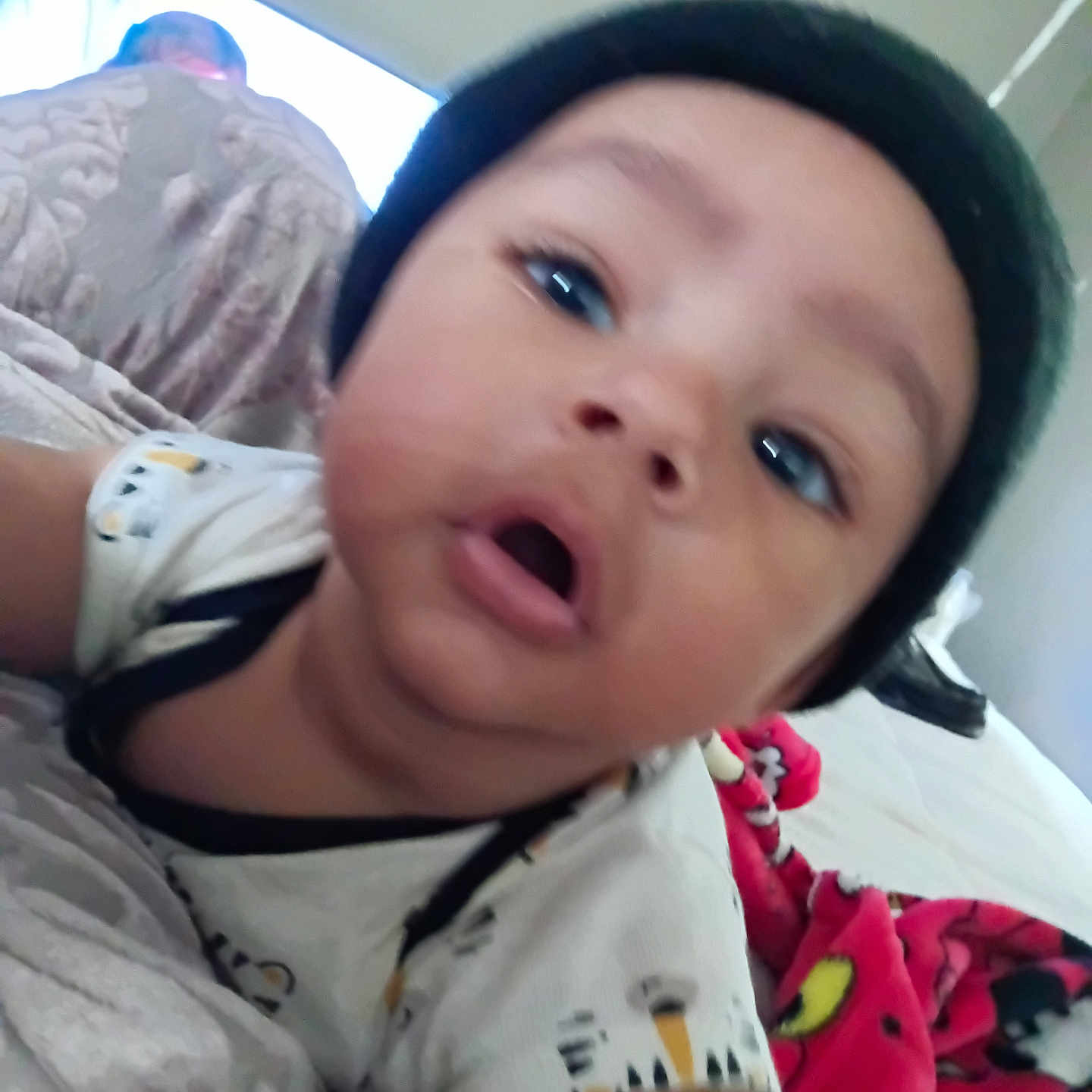 Ya'Quinn joined the competition — help win amazing prizes! baby, beanie, bed, blanket, child, closeup, clothing, cute, expression, face, headwear, indoor, infant, lying_down, patterned_clothing, person, red_blanket, skin, sleepwear, young_child