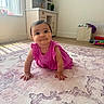 Harlow is registered to the contest to win money with this photo: baby, child, pink_dress, crawling, carpet, indoor, playroom, window, natural_light, curious, smile, floor, toy, furniture, young_child, head, hand, person, room, happy