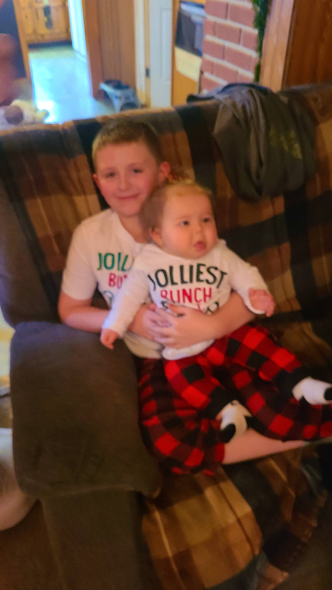 Greyson is registered to the contest to win money with this photo: christmas, christmas_eve, comfort, couch, event, fun, holiday, joy, lap, leg, living_room, pattern, person, plaid, shorts, sitting, smile, sock, t_shirt, tartan