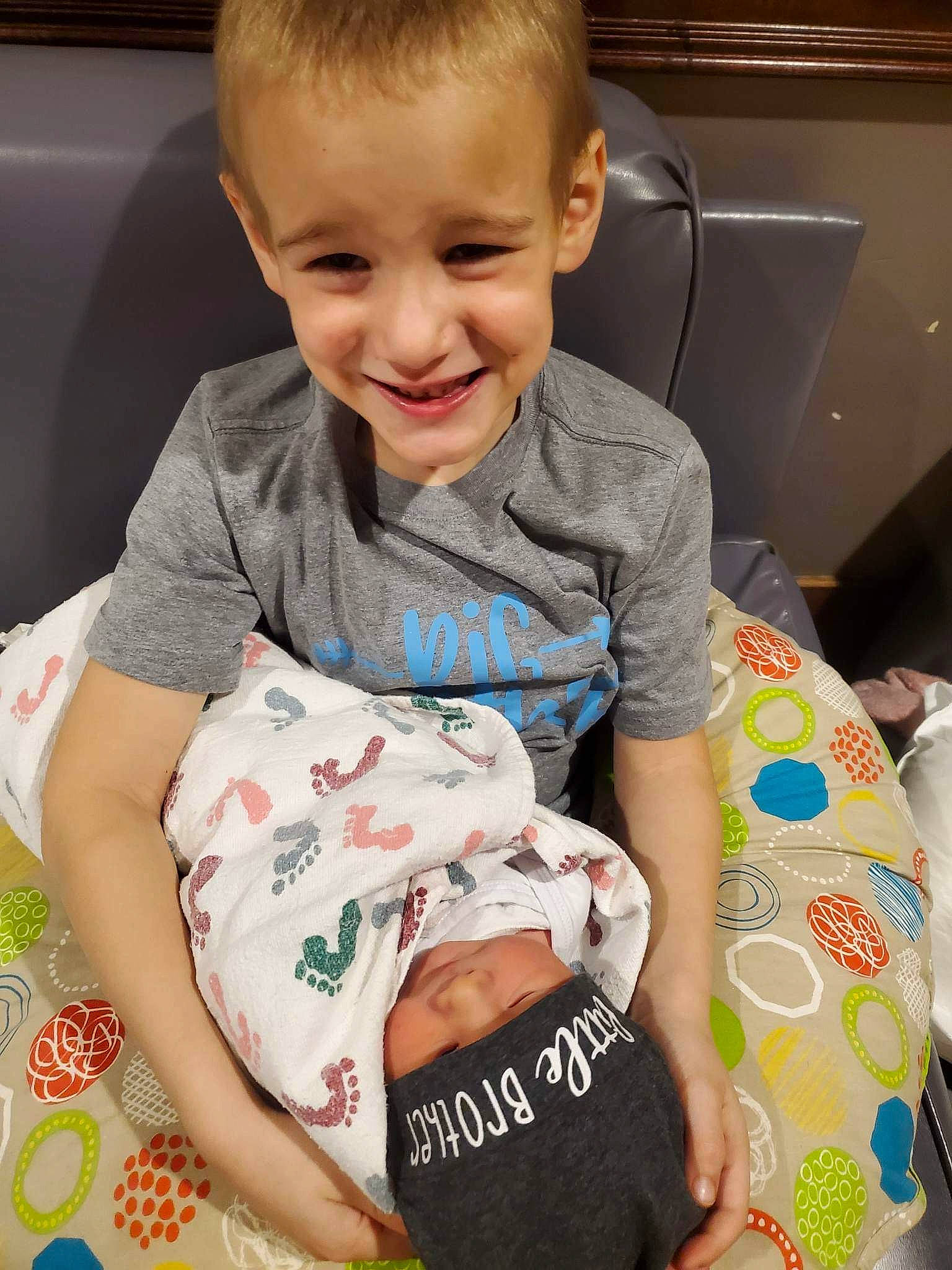 William is registered to the contest to win money with this photo: arm, baby, baby_toddler_clothing, cheek, child, comfort, face, facial_expression, finger, hand, happy, head, headwear, joy, leg, pattern, person, sitting, skin, sleeve