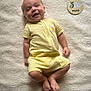 baby, infant, smiling, yellow_clothing, onesie, lying_down, blanket, soft_texture, wooden_plaque, koala, age_marker, happy, cute, portrait, skin, feet, arms, head, child, indoors