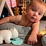 baby, infant, toy, plush_toy, baby_gym, teddy_bear, quilt, hand, face, blue_eyes, curious, indoors, window, natural_light, soft_toys, child, cute, skin, arm, playtime