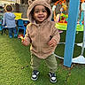 toddler, child, hoodie, bear_ears, sneakers, snack, playground, toys, grass, outdoor, smile, happy, person, baby, casual_clothing, daylight, playtime, fence, background_child, greenery