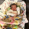 infant, baby, sleeping, blanket, mittens, cushion, footprint_pattern, cozy, resting, swaddled, soft, indoors, portrait, child, small, cute, peaceful, comfort, fabric, closeup