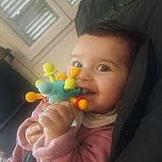 Anaïs participe au concours pour gagner de l'argent avec cette photo : baby, child, closeup, clothing, colorful_toy, couch, cute, face, hand, happy, indoor, infant, person, playtime, portrait, sitting, smiling, soft_lighting, toy, window