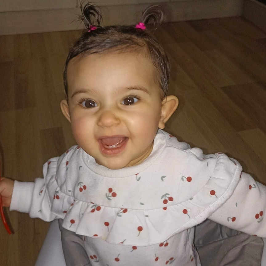 Anaïs a rejoint le concours — aidez-le/la à gagner de superbes lots ! baby, baby_walker, cheerful, child, clothing, cute, face, floor, hair_ties, happy, indoor, infant, kitchen, long_sleeve, person, pigtails, playful, smiling, toy, wooden_floor