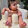 baby, infant, child, face, feet, toes, arm, inflatable_chair, bear_pattern, clothing, indoor, plant, curious, chubby_cheeks, sitting, soft_lighting, furniture, cute, food_on_face, relaxing