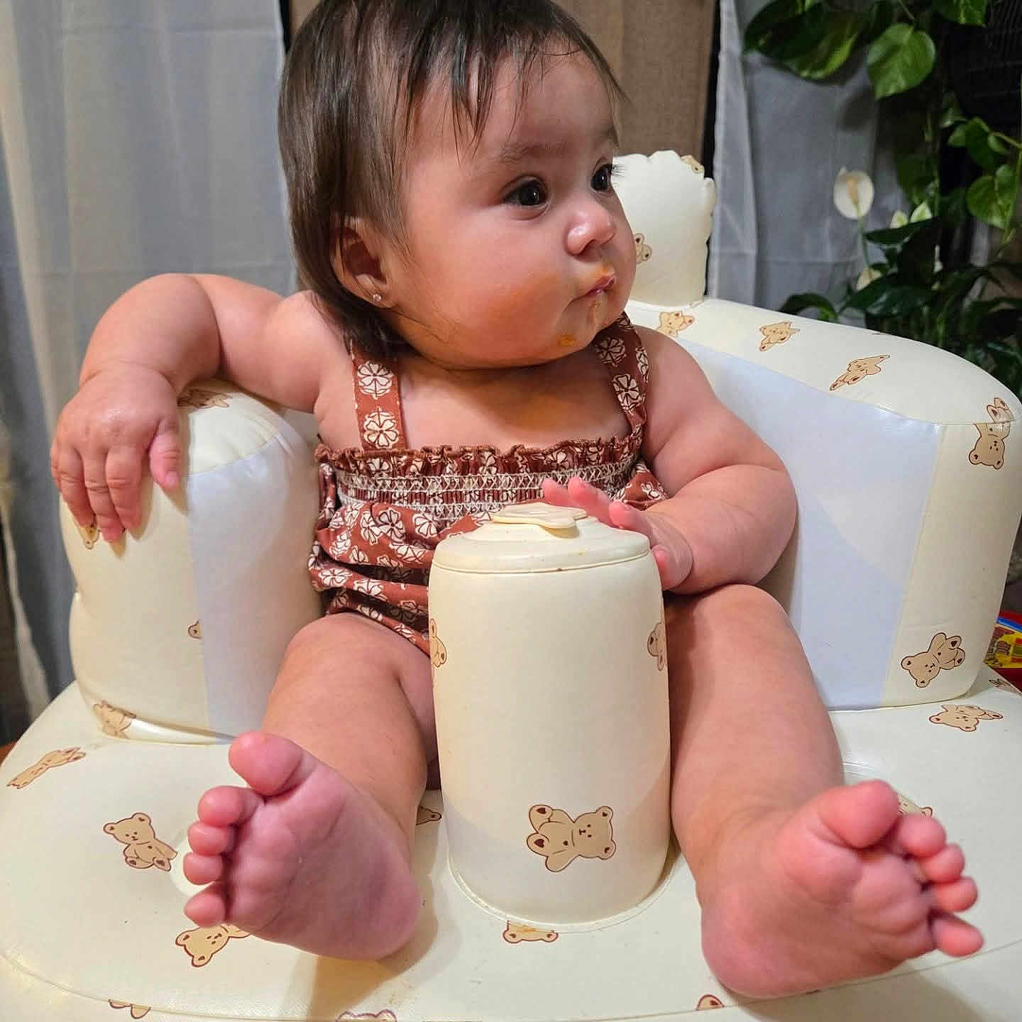 Evianna Envy Paez joined the competition — help win amazing prizes! arm, baby, bear_pattern, child, chubby_cheeks, clothing, curious, cute, face, feet, food_on_face, furniture, indoor, infant, inflatable_chair, plant, relaxing, sitting, soft_lighting, toes