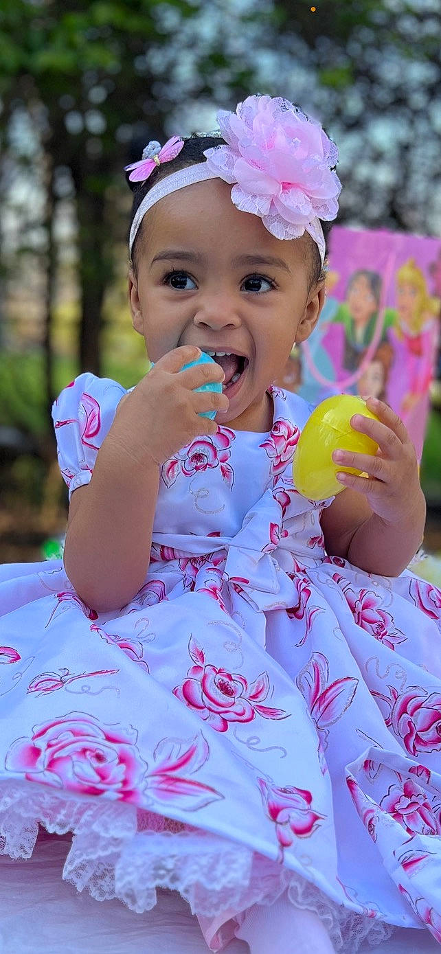 Sarai is registered to the contest to win money with this photo: baby, baby_toddler_clothing, beauty, child, dress, event, face, facial_expression, fun, grass, happy, headpiece, headwear, magenta, person, petal, photograph, pink, skin, smile