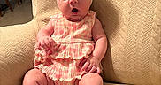 Jessica is registered to the contest to win money with this photo: baby, infant, child, headband, dress, armchair, beige, texture, furniture, indoor, home, kitchen, expression, cute, sitting, foot, hand, person, portrait, young