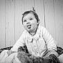 Ambre a rejoint le concours — aidez-le/la à gagner de superbes lots ! baby, child, tongue_out, black_and_white, portrait, cute, playful, blanket, soft_texture, wooden_background, infant, smiling, person, indoors, cozy, young_child, clothing, happy, face, hair_tie