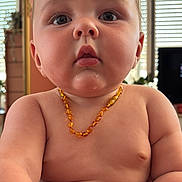 Elie participe au concours pour gagner de l'argent avec cette photo : baby, child, necklace, amber, skin, chubby, hand, blanket, indoor, window, curious, portrait, closeup, face, expression, young, furniture, room, natural_light, person