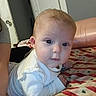 Aurora is registered to the contest to win money with this photo: baby, infant, child, portrait, face, blue_eyes, red_hair, curious, lying_down, crawling, white_clothing, long_sleeves, bed, bedspread, indoors, bedroom, door, furniture, close_up, photography