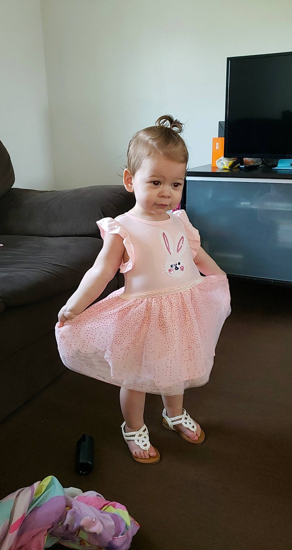 Nina is registered to the contest to win money with this photo: baby_toddler_clothing, couch, day_dress, dress, event, flash_photography, floor, flooring, formal_wear, fun, happy, joint, one_piece_garment, person, pink, sandal, shoulder, sitting, skin, television