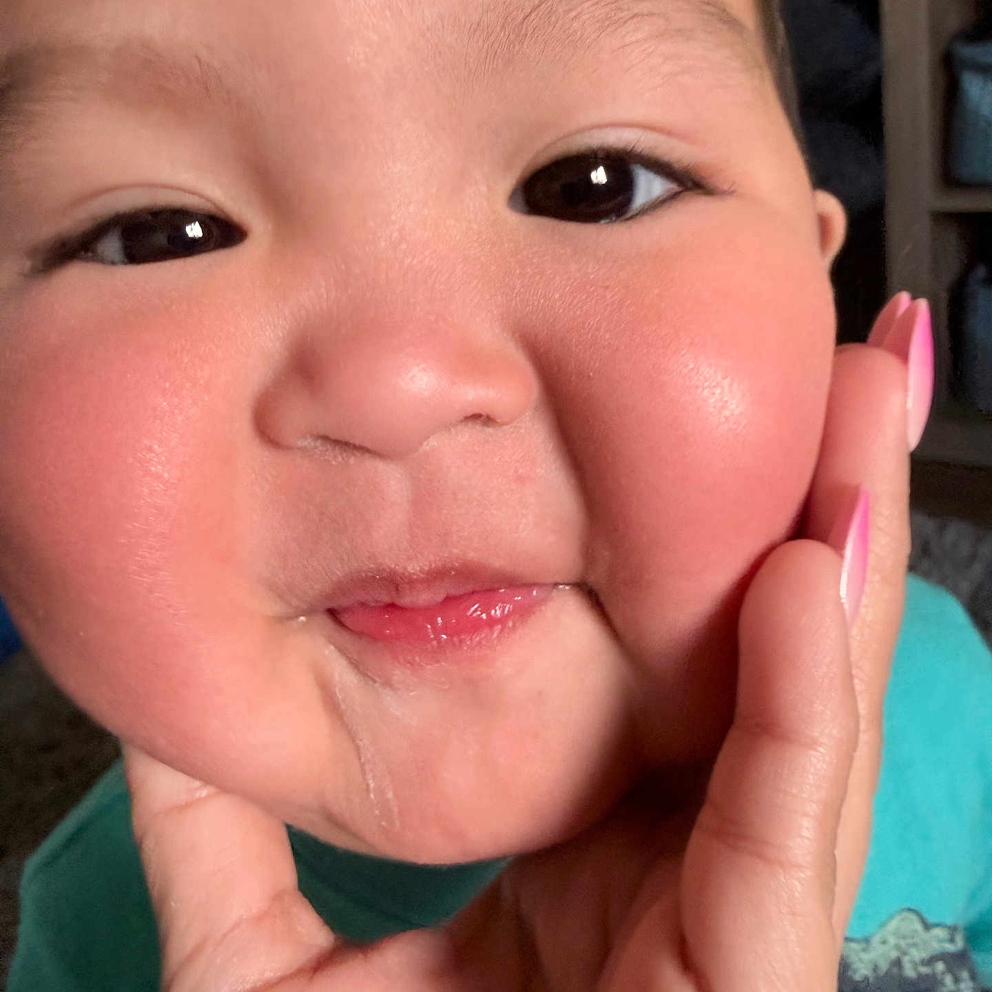 Lebron is registered to the contest to win money with this photo: baby, cheeks, child, close_up, drool, expression, eyes, face, fingertip, hand, indoor, person, pink_nails, portrait, rosy_cheeks, skin, smile, teal_shirt, toddler, young_child