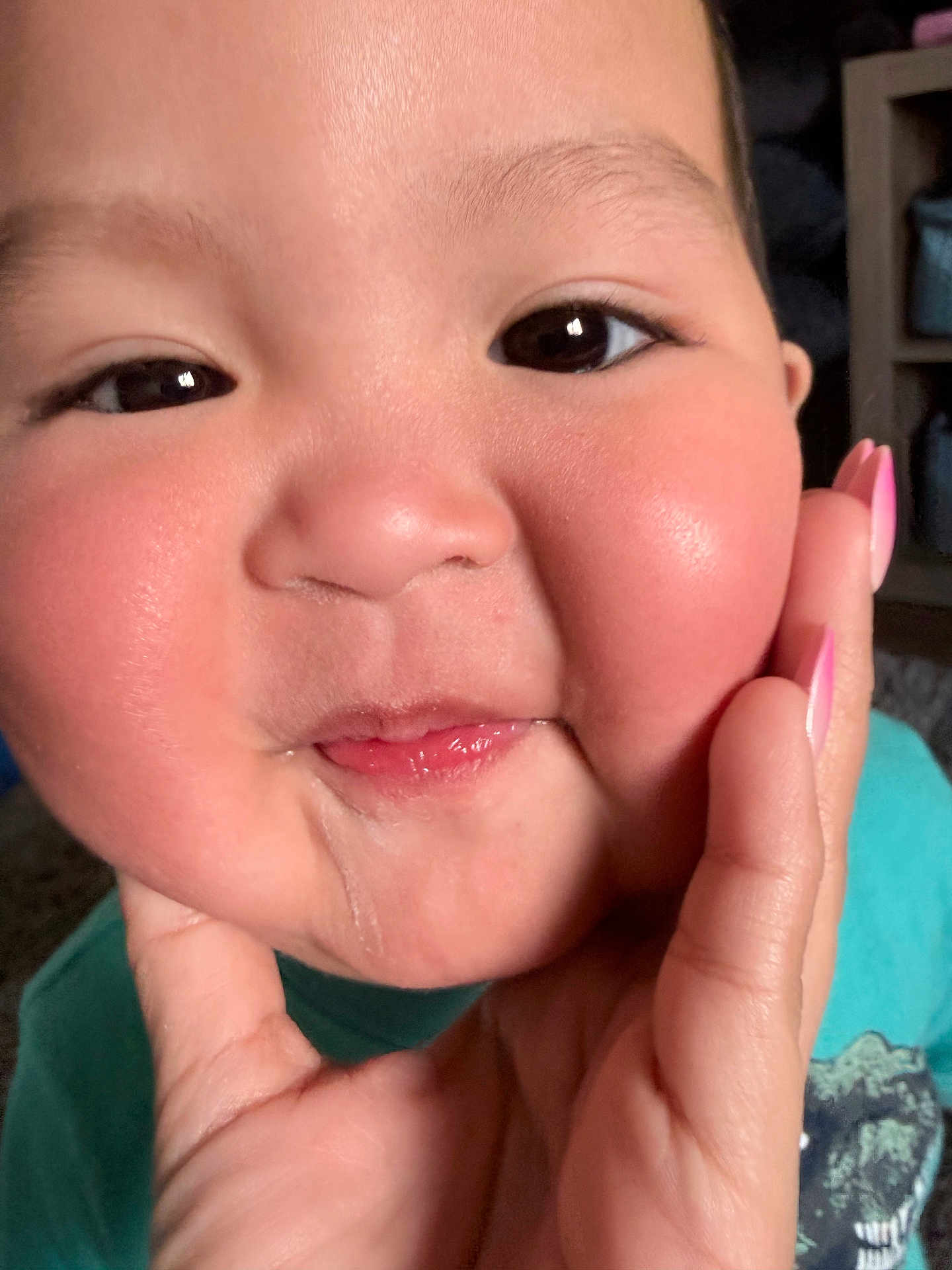 Lebron is registered to the contest to win money with this photo: child, toddler, baby, face, cheeks, drool, hand, pink_nails, eyes, close_up, rosy_cheeks, smile, skin, portrait, indoor, teal_shirt, fingertip, expression, person, young_child