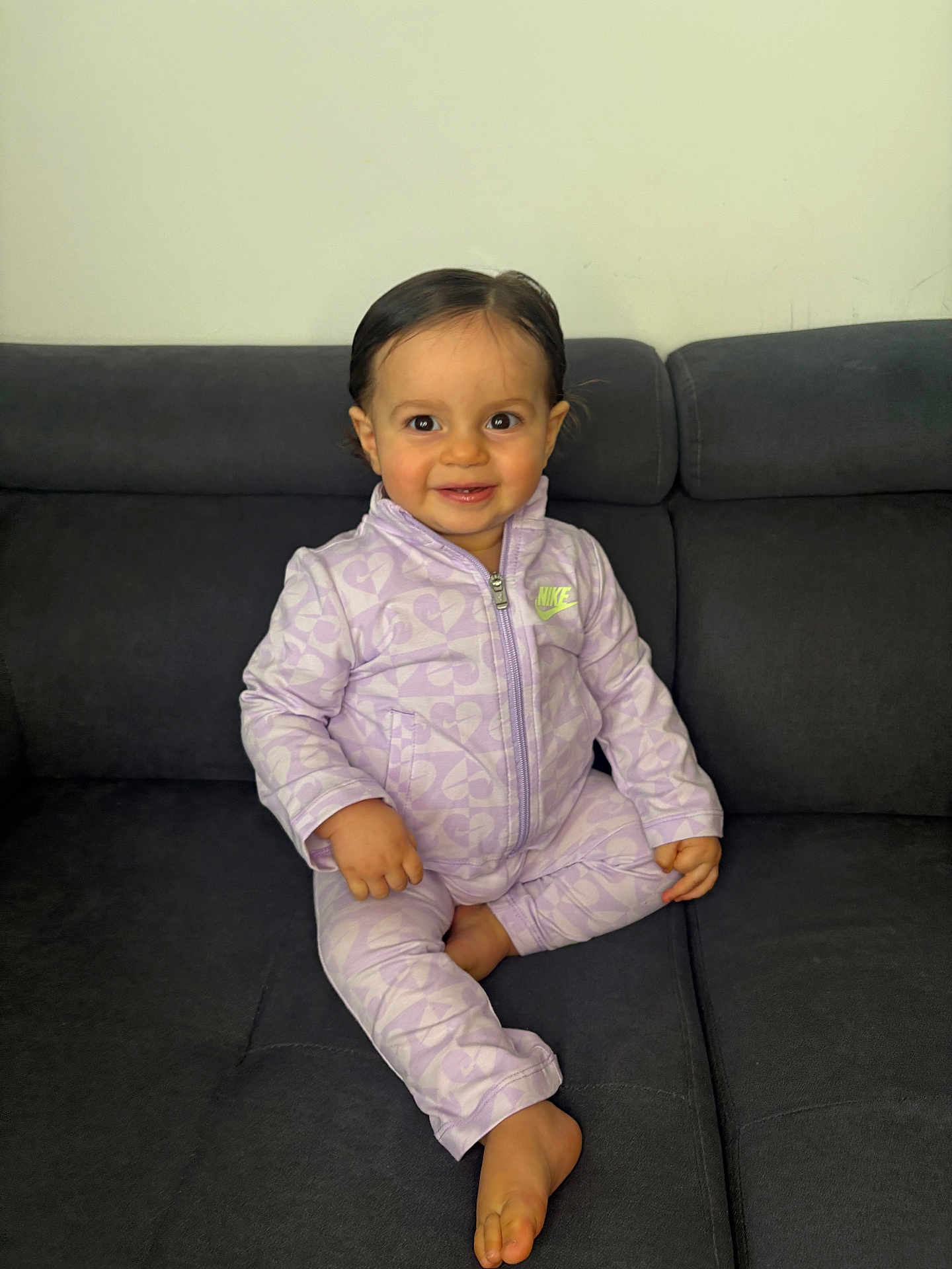 Alya a rejoint le concours — aidez-le/la à gagner de superbes lots ! toddler, child, smiling, sitting, couch, clothing, nike, purple, tracksuit, indoor, face, person, happy, hair, foot, hand, fabric, wall, home, portrait