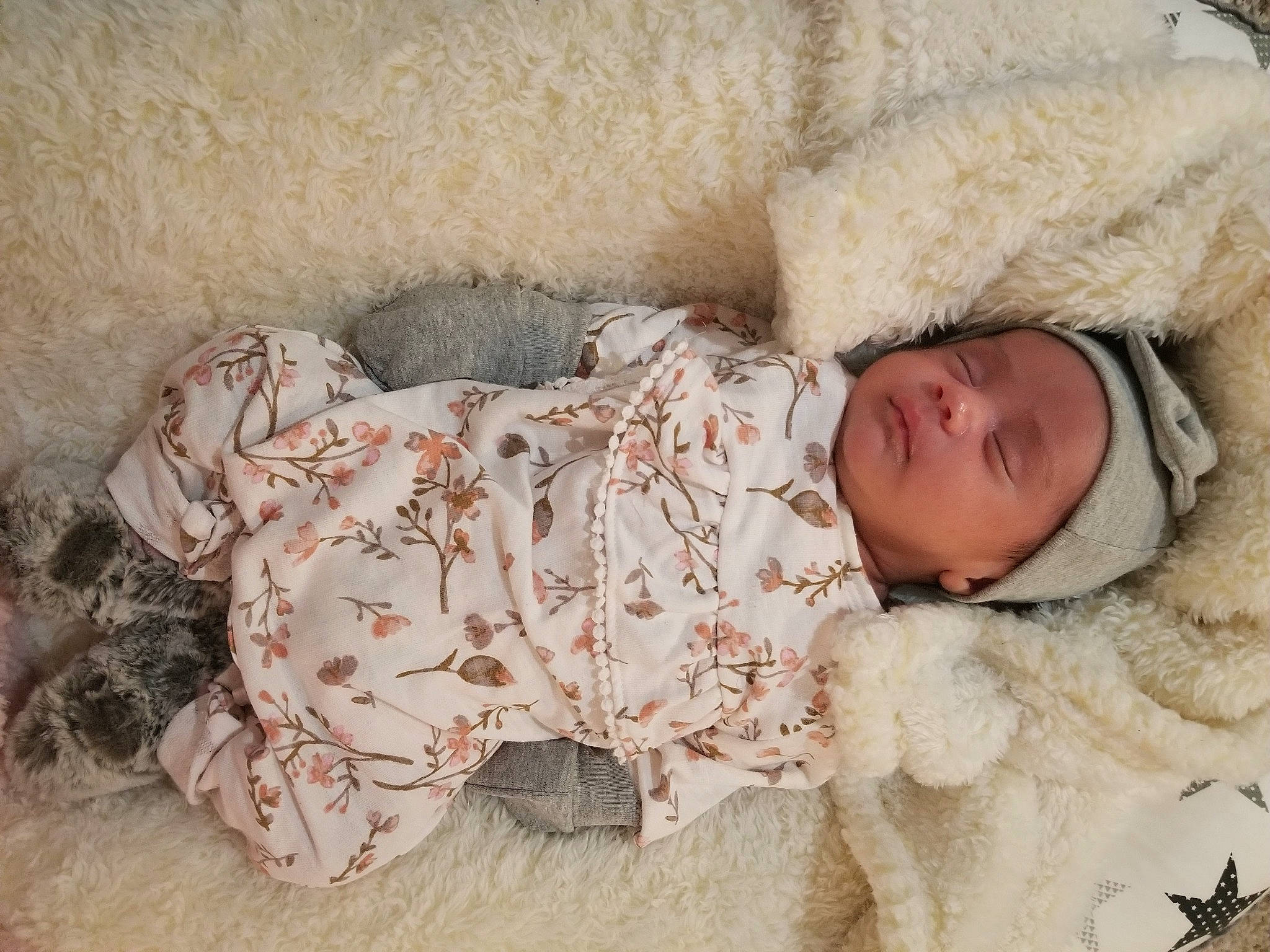 Hazel is registered to the contest to win money with this photo: baby, baby_sleeping, baby_toddler_clothing, cap, child, comfort, eye, fur, fur_clothing, head, headgear, headwear, knit_cap, linens, parka, pattern, person, sitting, skin, sleeve