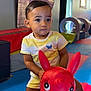 toddler, child, indoor, play_area, toy, inflatable, red, horse, colorful, mats, padded, shorts, tshirt, young_child, person, play, fun, expression, cute, floor