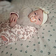 Lily a rejoint le concours — aidez-le/la à gagner de superbes lots ! baby, infant, pacifier, headband, blanket, onesie, patterned, sleepwear, cute, lying_down, child, soft_lighting, indoor, portrait, face, hand, clothing, bed, comfort, calm