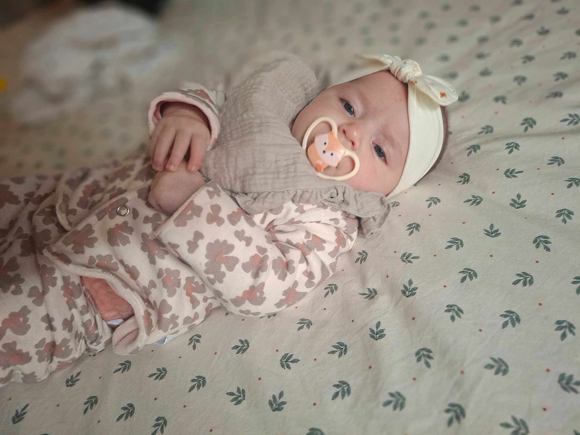 Lily a rejoint le concours — aidez-le/la à gagner de superbes lots ! baby, infant, pacifier, headband, blanket, onesie, patterned, sleepwear, cute, lying_down, child, soft_lighting, indoor, portrait, face, hand, clothing, bed, comfort, calm