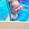 child, toddler, baby, swimming, pool, water, laughing, smiling, face, portrait, outdoor, summer, wet_hair, pool_float, mesh, blue, recreation, playful, daylight, happy