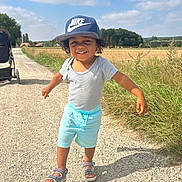 Matthew a rejoint le concours — aidez-le/la à gagner de superbes lots ! toddler, child, smiling, nike_cap, shorts, sandals, outdoor, sunny, gravel_path, grass, stroller, blue_sky, clouds, summer, happy, walking, nature, field, casual_clothing, daytime