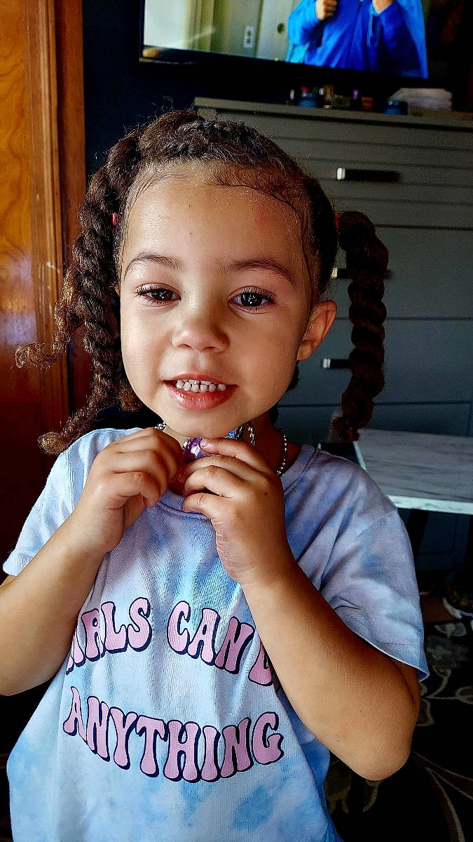 Kamryn is registered to the contest to win money with this photo: baby_toddler_clothing, black_hair, cheek, chin, dress, ear, eyebrow, eyelash, flash_photography, forehead, gesture, hairstyle, happy, lip, neck, nose, person, skin, sleeve, smile