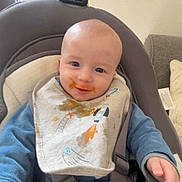 Kaïs participe au concours pour gagner de l'argent avec cette photo : baby, babymoov, bib, child, clothing, comfortable, couch, face, food, furniture, hand, happy, high_chair, indoor, infant, messy, person, pillow, smiling, text_overlay