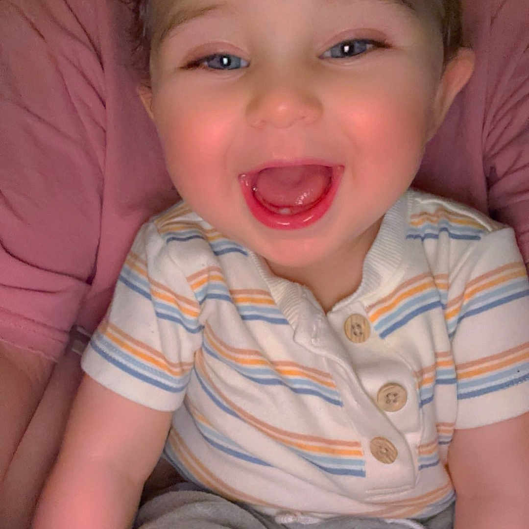 Adriel is registered to the contest to win money with this photo: baby, blue_eyes, casual_clothing, child, cute, face, grey_pants, happy, human, indoor, infant, joyful, mouth_open, person, portrait, short_hair, sitting, skin, smile, striped_shirt