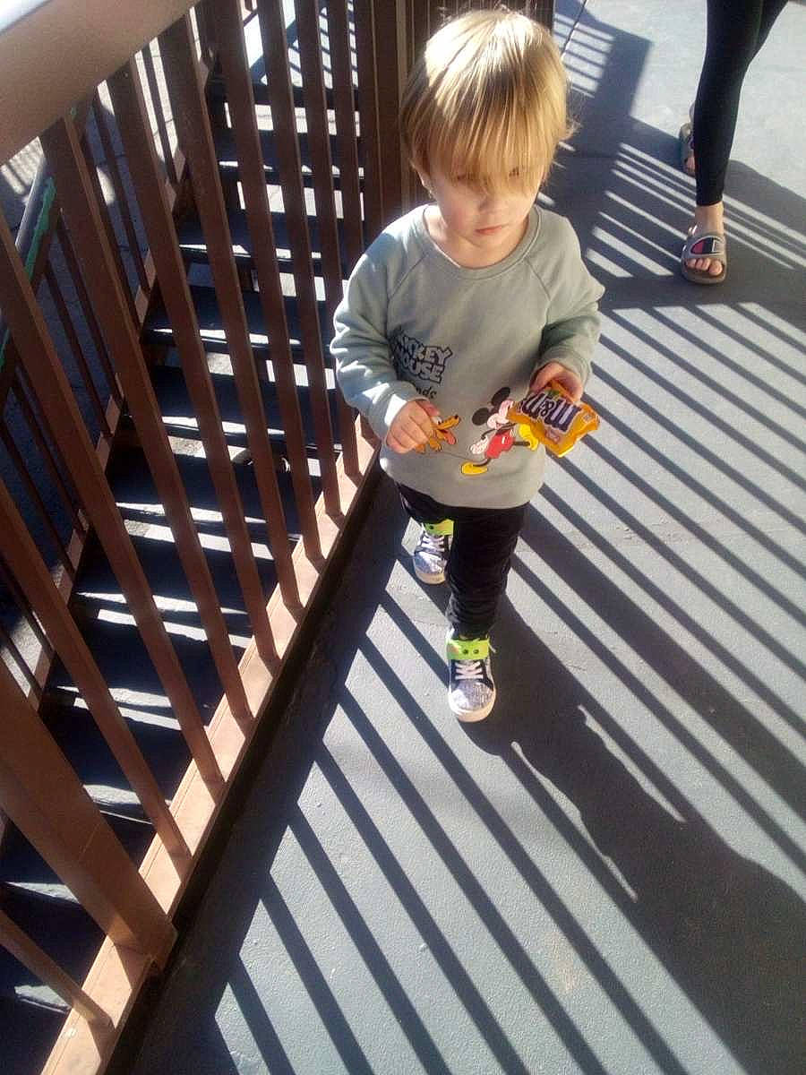 Elyas is registered to the contest to win money with this photo: child, deck, fence, flooring, foot, fun, handrail, hardwood, human_leg, leg, leisure, pattern, person, play, recreation, sneakers, t_shirt, thigh, toddler, wood