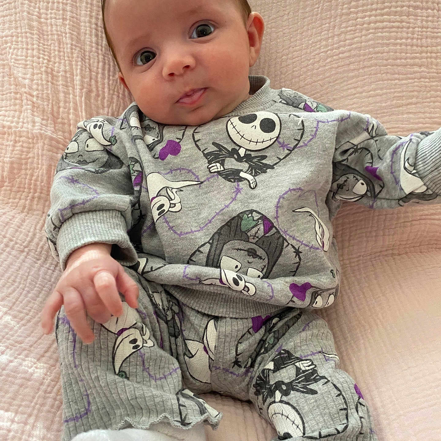 Penelope is registered to the contest to win money with this photo: baby, infant, child, cute, clothing, sitting, pink_blanket, portrait, face, hand, footwear, expression, indoors, apparel, patterned_outfit, cozy, soft_texture, young_child, looking_at_camera, playful