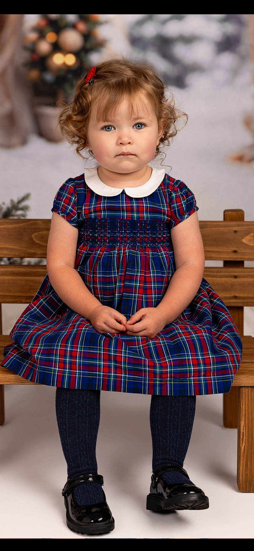 Mimi joined the competition — help win amazing prizes! black_shoes, blue_eyes, child, childhood, curly_hair, cute, fashion, holiday_background, indoor, innocent, navy_tights, plaid_dress, portrait, red_hair_clip, serious_expression, sitting, studio_photo, toddler, wooden_bench, young_girl