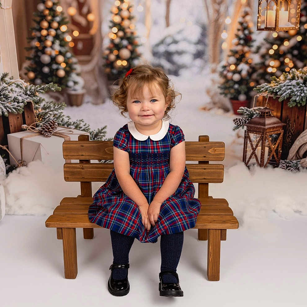 Mimi joined the competition — help win amazing prizes! black_shoes, child, christmas_tree, cozy, curly_hair, festive, girl, holiday_decor, indoors, lantern, plaid_dress, portrait, red_bow, smiling, snow_effect, studio_photo, toddler, winter_theme, wooden_bench, wrapped_presents