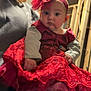 adult, baby, celebration, child, closeup, curious, cute, face, fashion, female, headband, holding, indoor, long_sleeve, person, portrait, red_dress, smile, unfinished_wall, wooden_frame