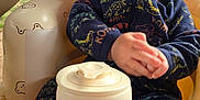 Karson is registered to the contest to win money with this photo: baby, child, smiling, clapping, onesie, dinosaur_pattern, seat, bear_pattern, container, outdoor, dog, black_dog, happy, infant, face, head, hands, toy, furniture, grass