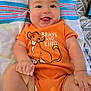 Karson is registered to the contest to win money with this photo: baby, infant, smiling, tongue_out, orange_onesie, simba, disney, brave_and_kind, blanket, patterned_blanket, cute, happy, child, person, lying_down, playful, chubby_cheeks, indoors, toddler, young_child
