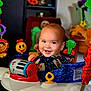 Karson is registered to the contest to win money with this photo: activity_center, baby, carpet, child, colorful, cute, expression, face, furniture, happy, home, indoor, infant, pajamas, person, play, seat, smiling, toy, young
