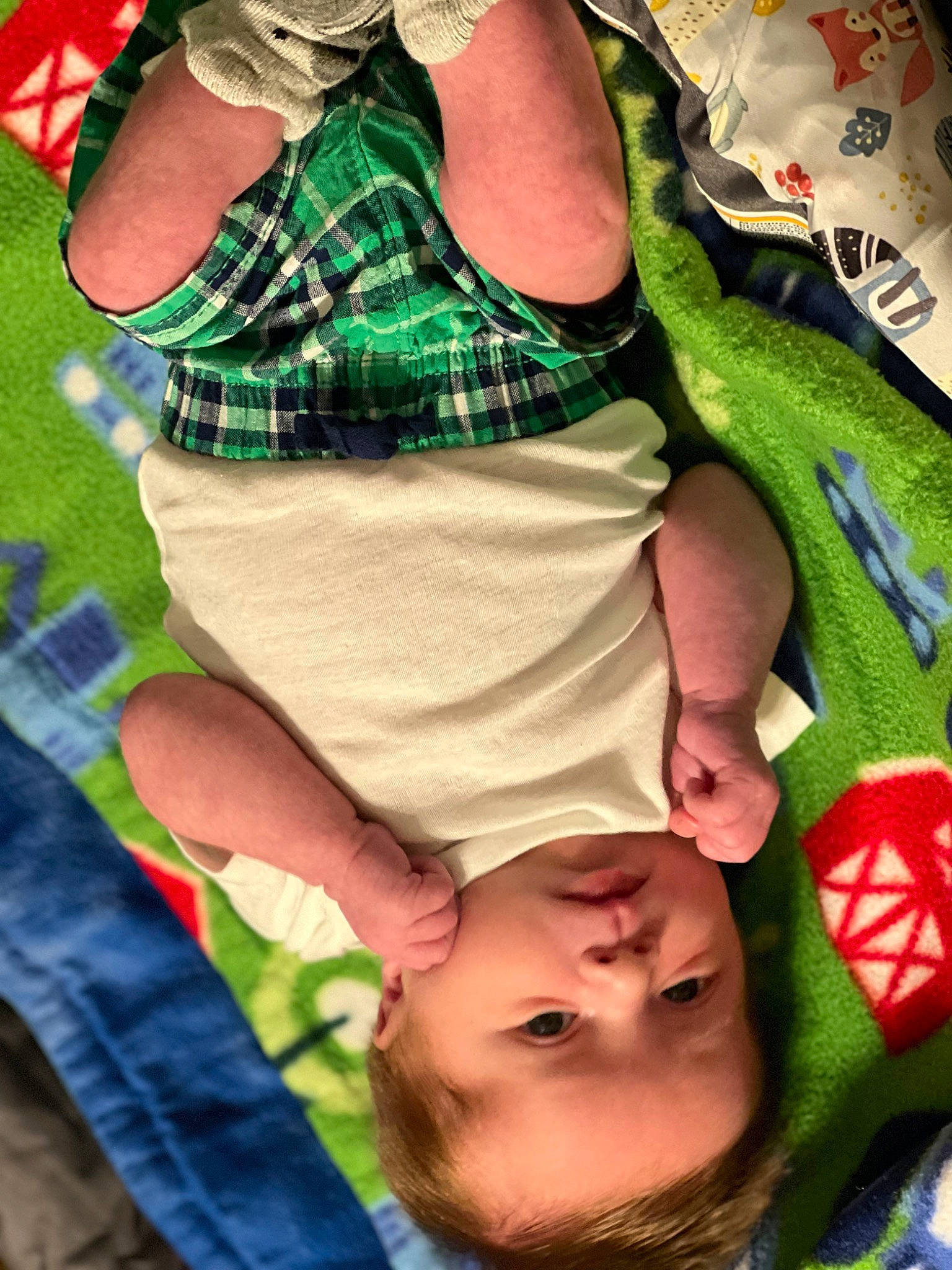 Xavier is registered to the contest to win money with this photo: baby, baby_toddler_clothing, finger, fun, gesture, grass, green, happy, human, leaf, leg, people, person, product, red, sleeve, tartan, textile, thigh, toddler