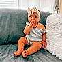 Kelya participe au concours pour gagner de l'argent avec cette photo : baby, child, sitting, couch, headband, bow, teething_toy, blue_clothing, plush_pillow, indoor, cute, infant, soft_lighting, curious, happy, skin, hand, foot, furniture, portrait